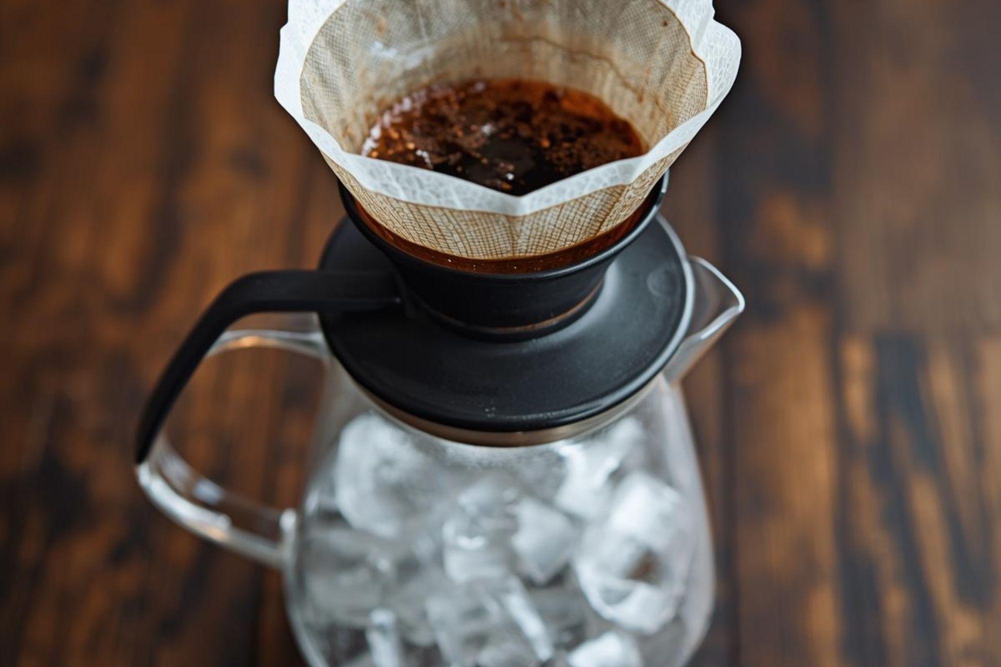 A photo showing ice cubes in the bottom of the server with the rinsed filter ready above it.