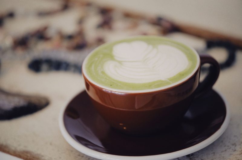 A close-up of a vibrant green matcha latte with a smooth, velvety microfoam layer on top, served in a stylish mug.